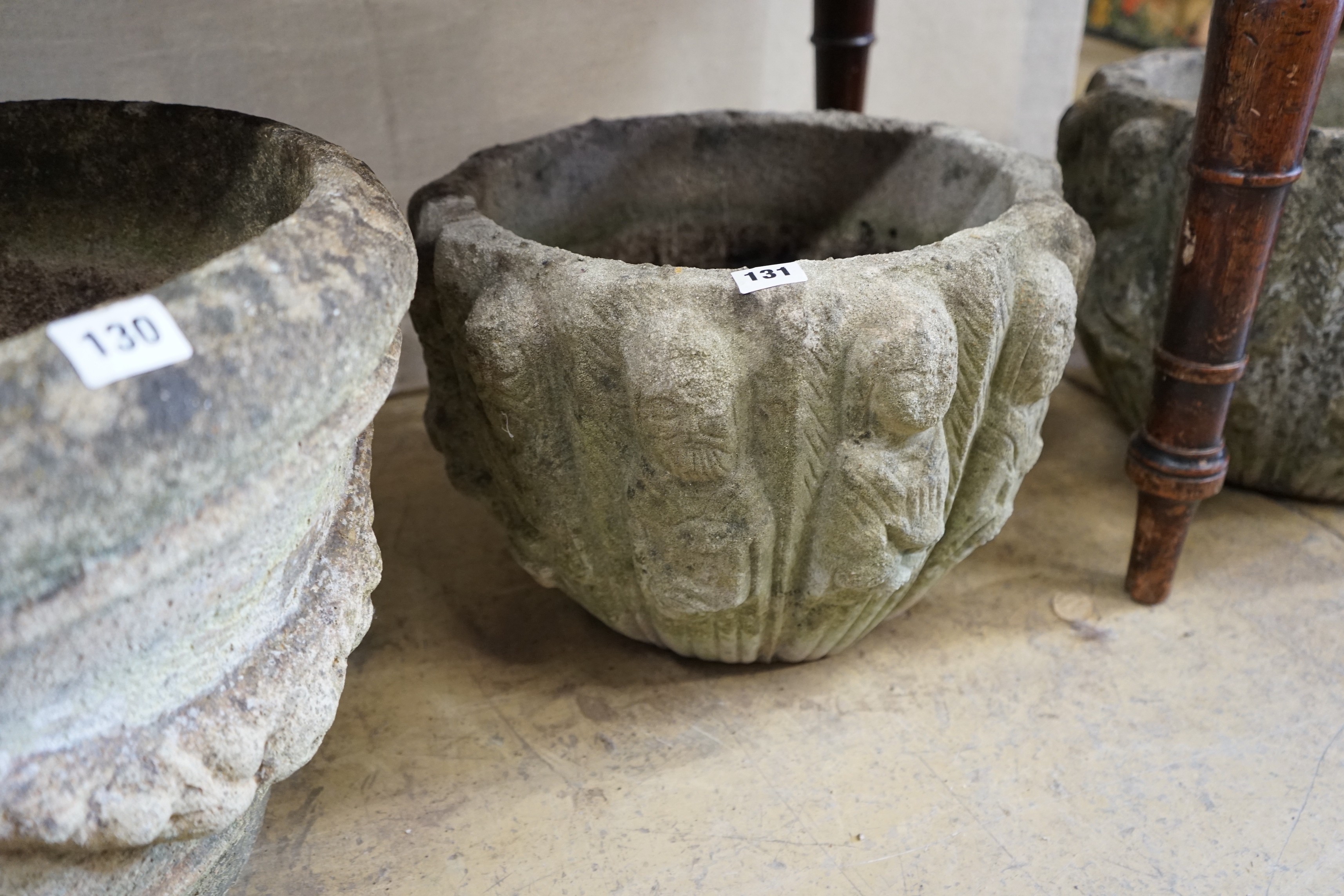 A pair of circular reconstituted stone '12 apostles' garden urns diameter 40cm height 28cm